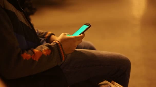 Niño con smartphone en un parque de la ciudad por la noche
 - Metraje, vídeo
