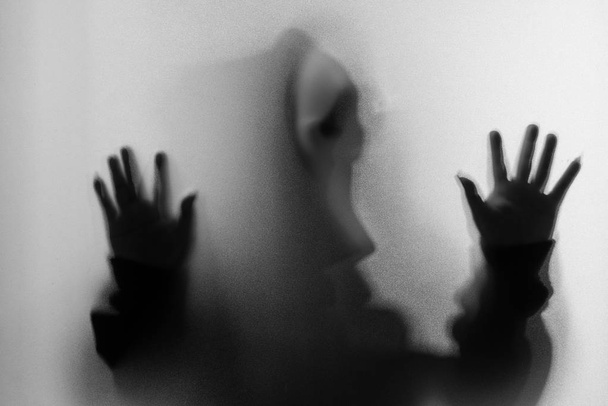 Θόλωσης σκιάς του ανθρώπου τρόμου σε ουρλιάζοντας μάσκα και χέρι αγγίζει το - Φωτογραφία, εικόνα