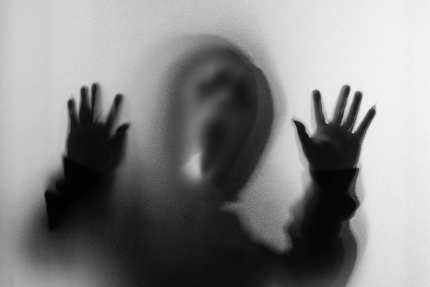 Θόλωσης σκιάς του ανθρώπου τρόμου σε ουρλιάζοντας μάσκα και χέρι αγγίζει το - Φωτογραφία, εικόνα