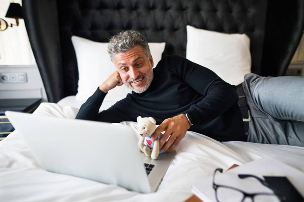 Mature businessman with laptop in a hotel room. - Fotografie, Obrázek