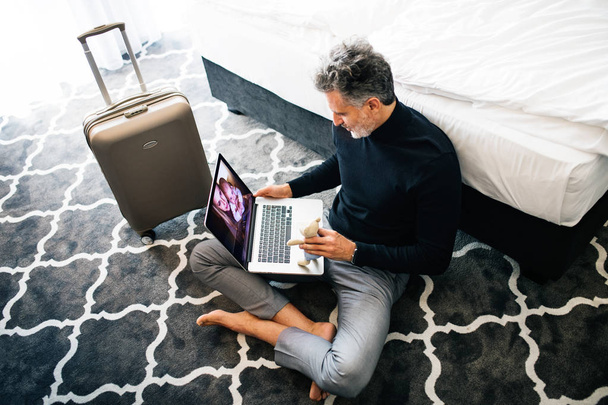 Mature businessman with laptop in a hotel room. - Zdjęcie, obraz
