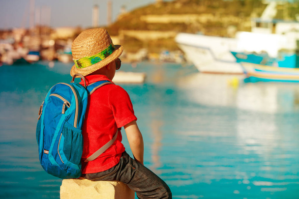 pieni poika katselee perinteisiä veneitä Maltalla
 - Valokuva, kuva