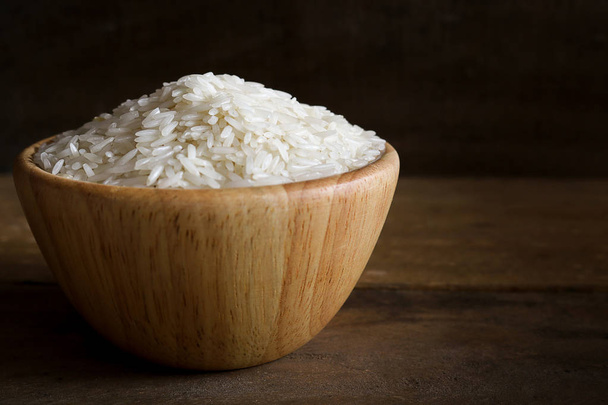 Jasmine rice in wooden bowl on rustic wood background - Photo, Image