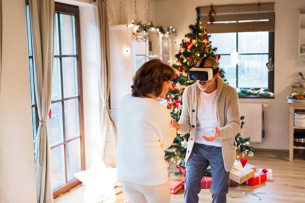 Senior couple in front of Christmas tree with VR goggles. - Photo, Image