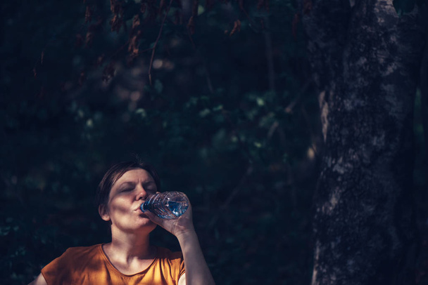 Mujer bebiendo agua al aire libre
 - Foto, imagen