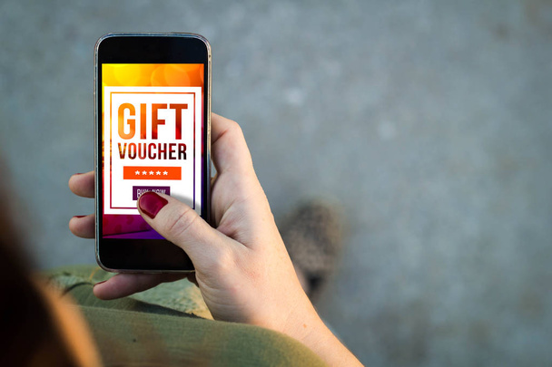 mobile marketing concept: woman using smartphone with gift voucher on screen - Foto, Imagen