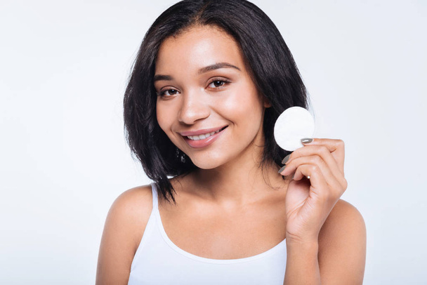 Pleasant smiling young woman holding a cotton pad - Fotoğraf, Görsel