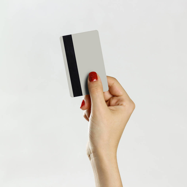 Female hand holding credit card. Isolated on gray background. Cl - Фото, изображение