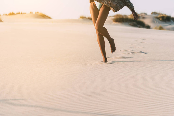 Piernas de una joven mujer negra caminando en la arena en una duna del desierto
 - Foto, Imagen