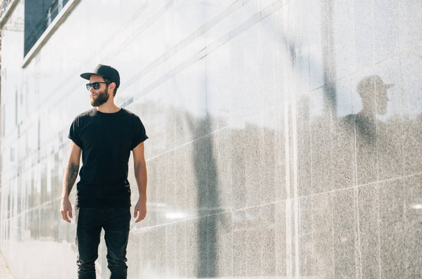 Hipster man wearing black T-shirt and a black hat with space for - Photo, image