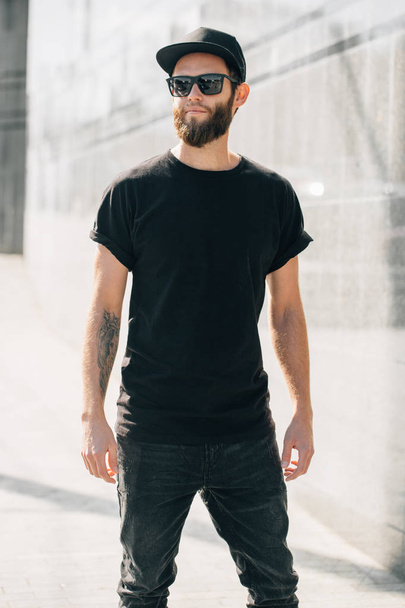 Hipster man walking wearing black jeans, t-shirt and a baseball  - Fotoğraf, Görsel