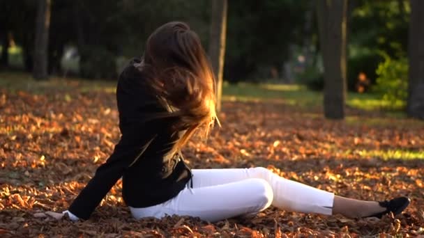 Giovane bella ragazza bruna seduta sulla lettiera di foglie gialle
 - Filmati, video