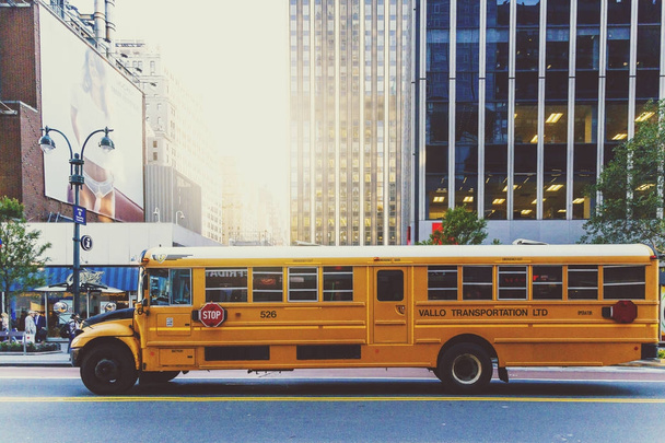 Yellow school bus driving along a street in Manhattan - Фото, изображение