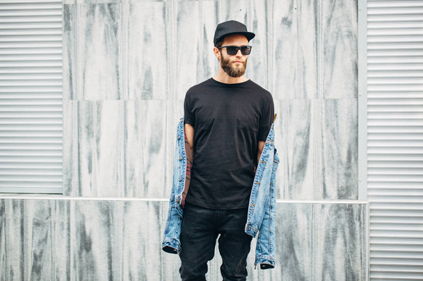 Hipster man walking wearing black jeans, t-shirt and a baseball  - 写真・画像