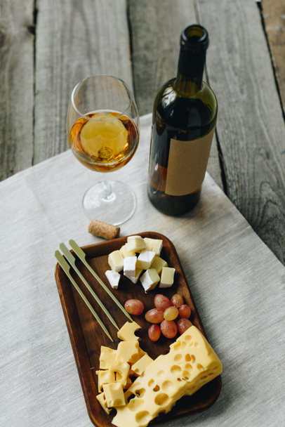 Glass with wine and plate with cheese and grapes - Photo, Image