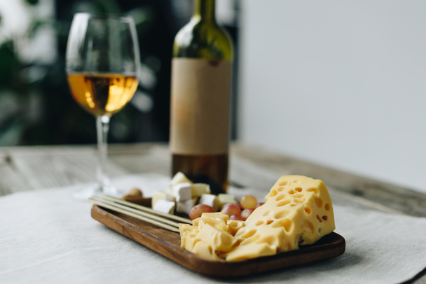 Glass with wine and plate with cheese and grapes - Photo, image
