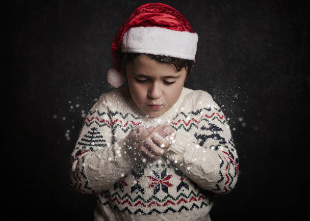 niño pequeño sopla nieve de las manos en Navidad
 - Foto, Imagen