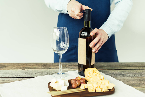 сомелье открывает бутылку белого вина
   - Фото, изображение