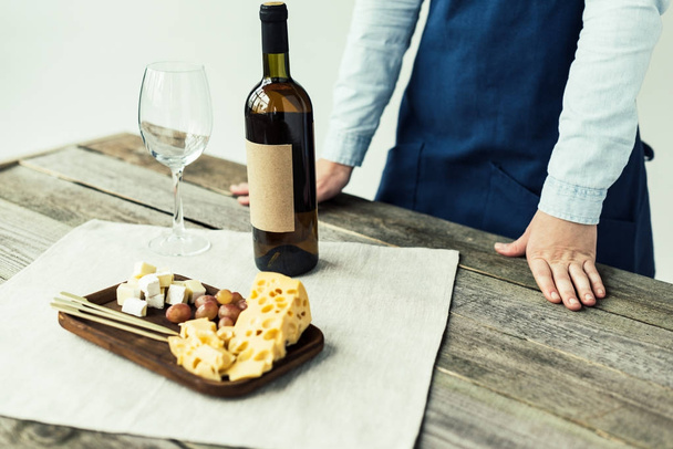 Sommelier ayakta masada şarap şişesi ile - Fotoğraf, Görsel
