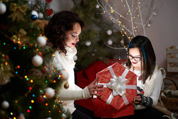 Cheerful young girl celebrating Christmas with her mother at hom - 写真・画像