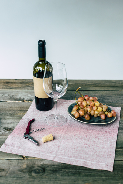 Botella de vino con vaso vacío y uvas
 - Foto, Imagen