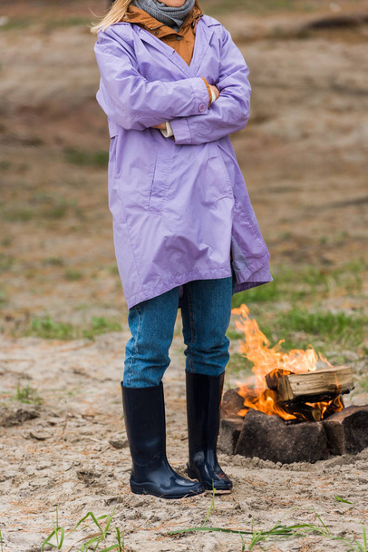 lonely woman in raincoat near bonfire - Φωτογραφία, εικόνα