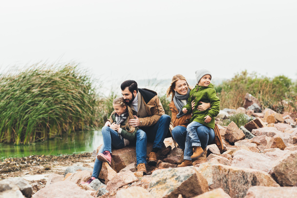 Perhe istuu kivinen rannikolla
 - Valokuva, kuva
