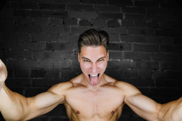 Young muscular bodybuilder fitness model posing against a brick wall loft fitness club. Beauty Ring flash. - Valokuva, kuva