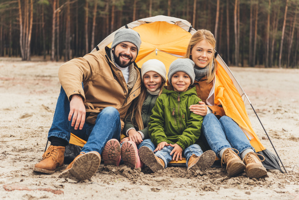 family sitting next to camping tent - Photo, Image