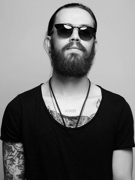 бородатый мужчина с татуировкой и солнцезащитными очками
 - Фото, изображение