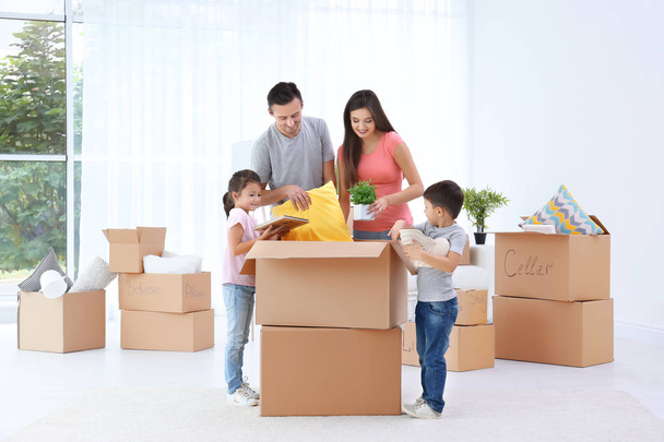 Happy family unpacking moving boxes in room at new home - Φωτογραφία, εικόνα