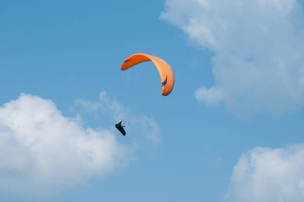 Parapente volando en el cielo azul sobre el fondo de las nubes
. - Foto, Imagen