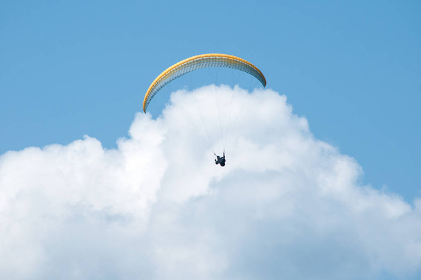 Gleitschirm fliegt in den blauen Himmel vor dem Hintergrund der Wolken. - Foto, Bild