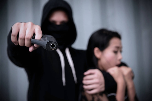 Homme criminel en sweat à capuche arme pointée avec victime
 - Photo, image