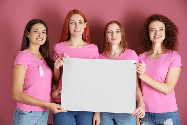 Young women in pink t-shirts holding blank sheet of paper on color background. Breast cancer awareness concept - Fotó, kép