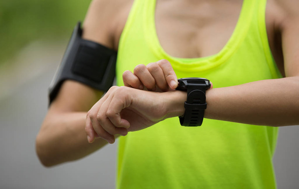 young fitness woman setting the sports watch on forest trail - Foto, Imagen