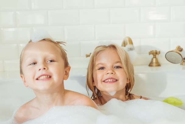 kids playing in bathtub with foam - Фото, изображение
