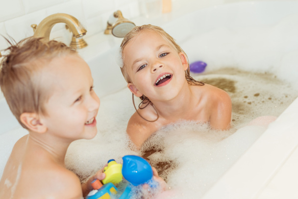 kids playing in bathtub with foam - Photo, Image