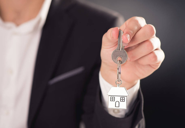 Agent immobilier donnant des clés de maison sur un porte-clés en forme de maison d'argent
 - Photo, image