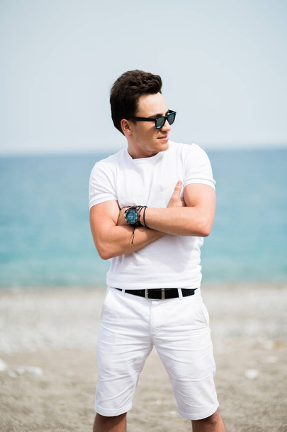 Portrait of young man in sunglasses smiling on the beach - Fotografie, Obrázek