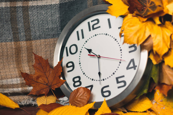 Φθινόπωρο εποχή. Ρολόι τοίχου ανάμεσα στα πολύχρωμα φύλλα. - Φωτογραφία, εικόνα