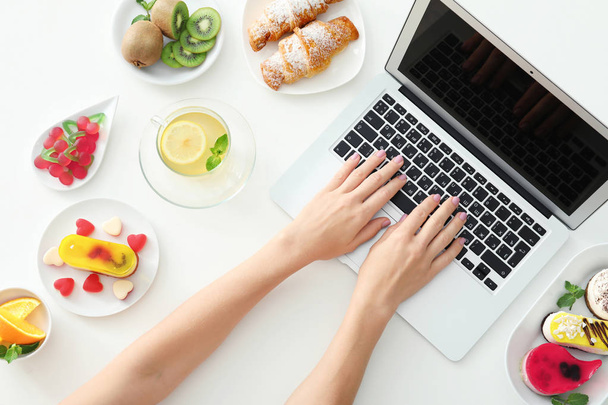 Hands of food blogger with laptop and different products on white table - Фото, изображение