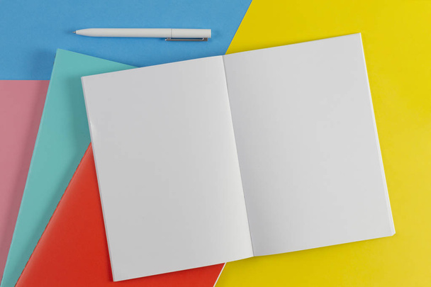 Ανοίξτε το σημειωματάριο, Λευκό στυλό και πολύχρωμο σημειωματάρια σε μπλε και κίτρινο φόντο - Φωτογραφία, εικόνα