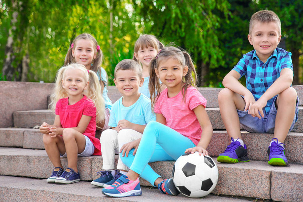 Cute little children with ball sitting on stairs in city park - Zdjęcie, obraz