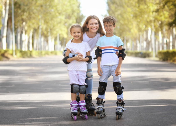 Mother with son and daughter rollerskating in park - Фото, изображение
