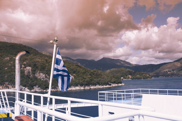 The Greek flag on the ship against the background of the sea of islands. Sea voyage in the Ionian sea. - Photo, image