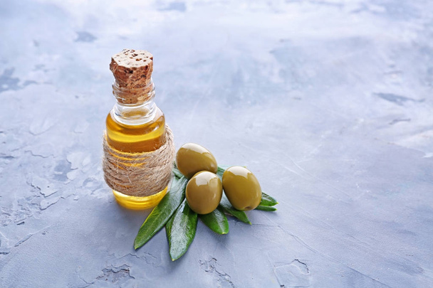Glass bottle with olive oil on light background - Фото, изображение