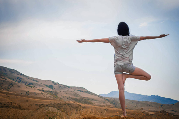 Atrakcyjna młoda kobieta jest Praktykowanie jogi na szczycie wysokiej góry wieczorem - Zdjęcie, obraz