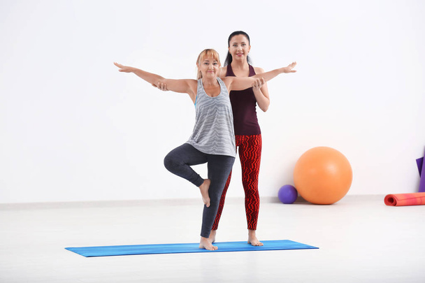 Mature woman with personal yoga instructor indoors - Zdjęcie, obraz
