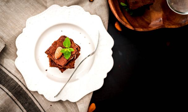 exquisite freshly prepared chocolate brownie cake on a white porcelain plate top view - Foto, imagen